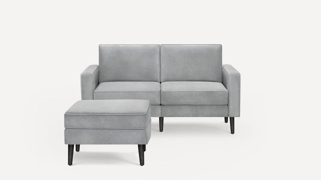 Light gray modern loveseat sofa with matching ottoman, both featuring smooth upholstery and dark wooden tapered legs.