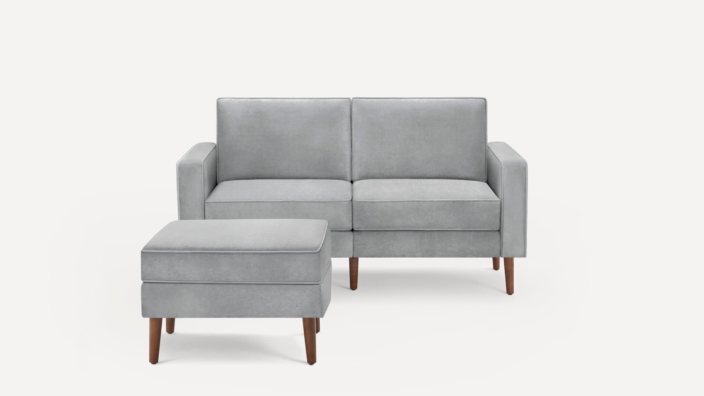 Light gray modern loveseat with matching ottoman, upholstered fabric and tapered wooden legs.