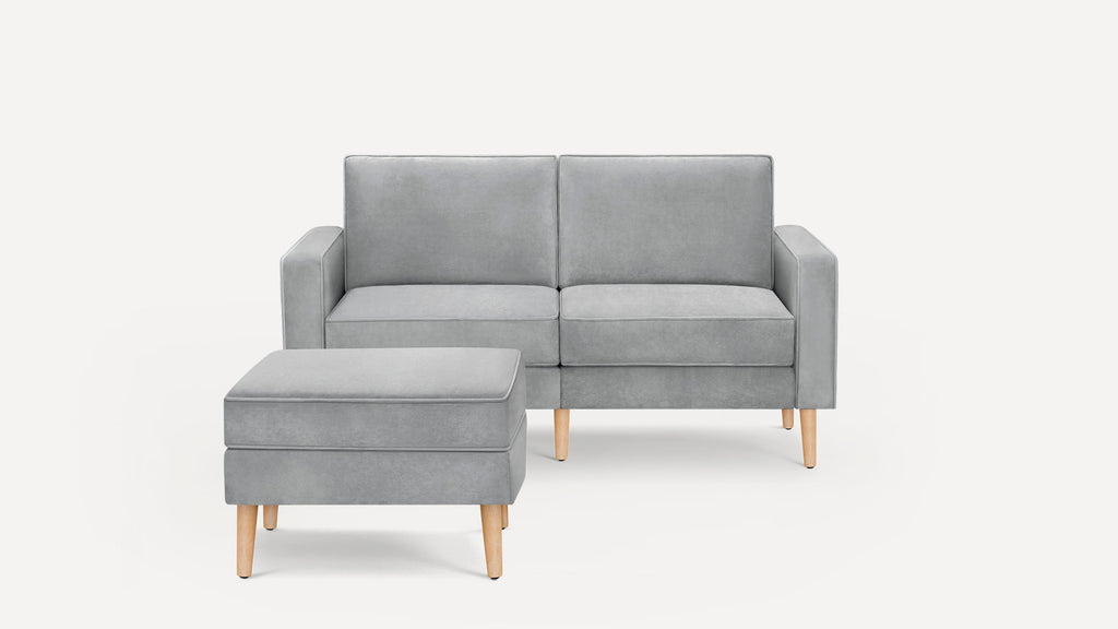 Modern light gray two-seater sofa with matching ottoman, both featuring wooden legs and clean, minimalist design.