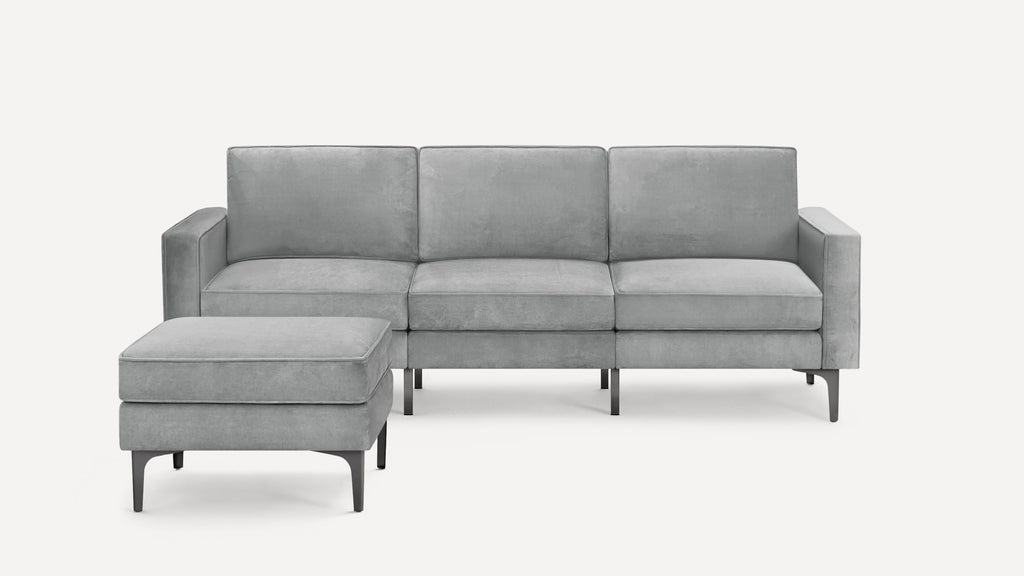 Modern light gray three-seater sofa with matching ottoman, plush cushions, and sleek black metal legs on white background.