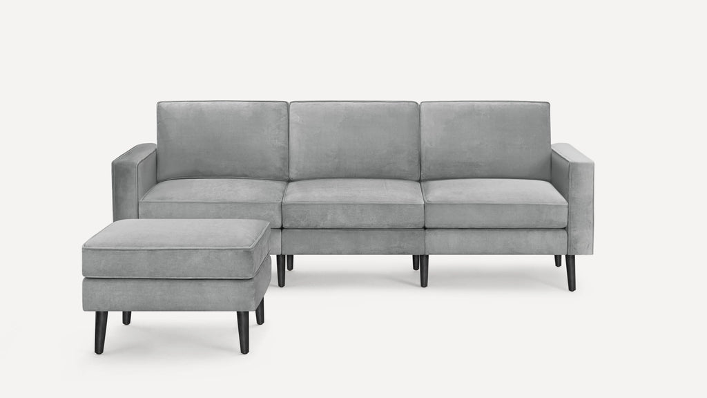 Modern light gray three-seater sofa with matching ottoman, featuring clean lines and black tapered wooden legs.