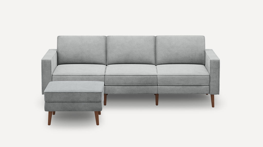 Modern light gray three-seater sofa with matching ottoman, wooden tapered legs, and clean, straight armrests on a white background.