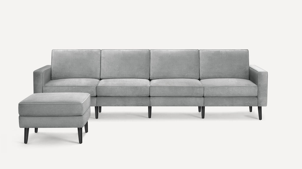Modern light gray sectional sofa with slim black legs and matching ottoman, featuring clean lines and plush cushions.