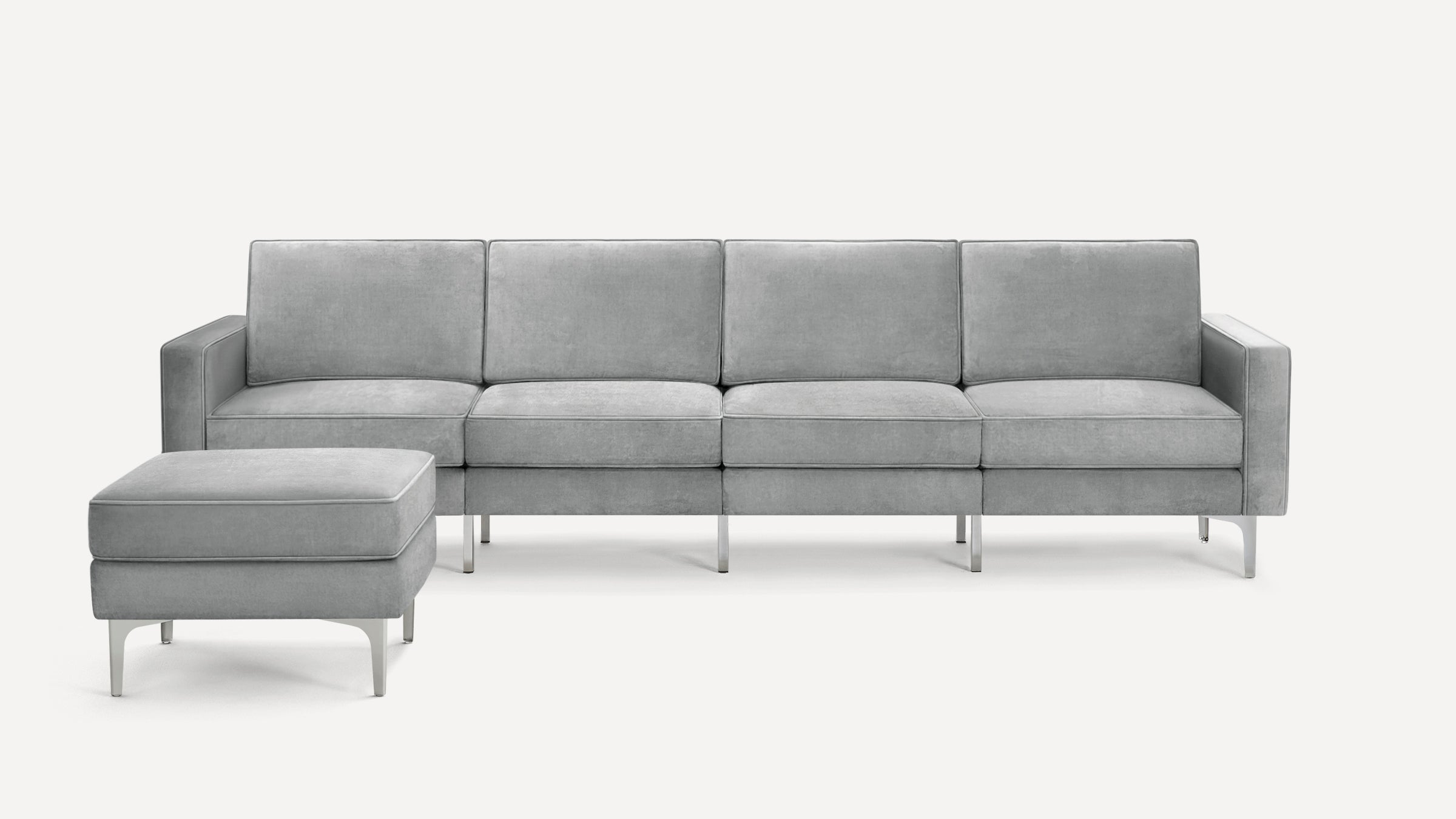 Light gray modern sofa with four cushioned seats and matching ottoman, featuring slim metal legs and a minimalist design.
