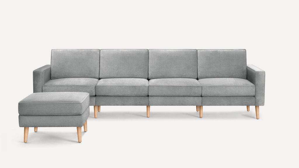 Modern light gray fabric sofa with clean lines, wooden legs, and matching ottoman, designed for contemporary living spaces.