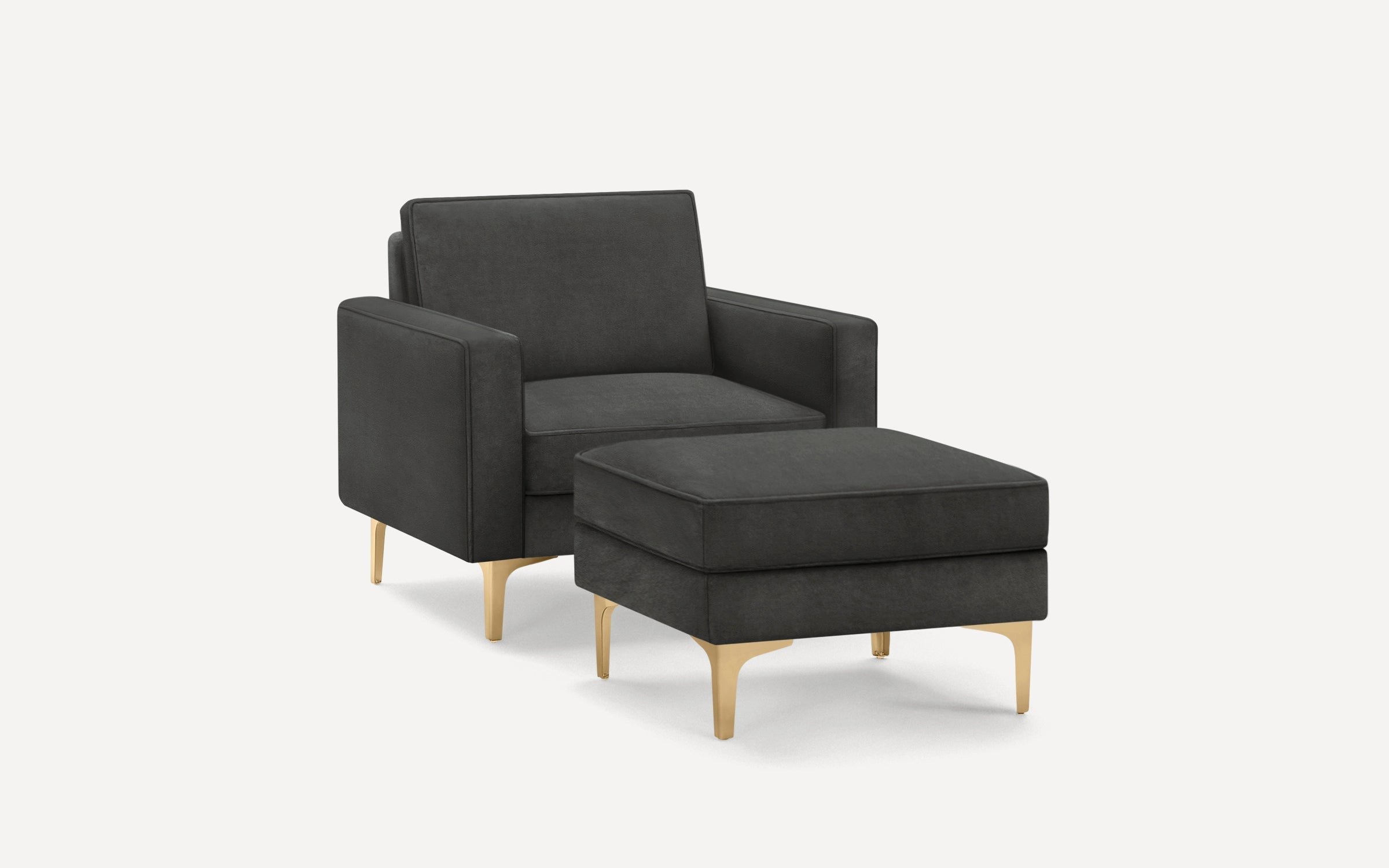 Dark grey upholstered armchair with matching ottoman featuring sleek gold metal legs on a white background.