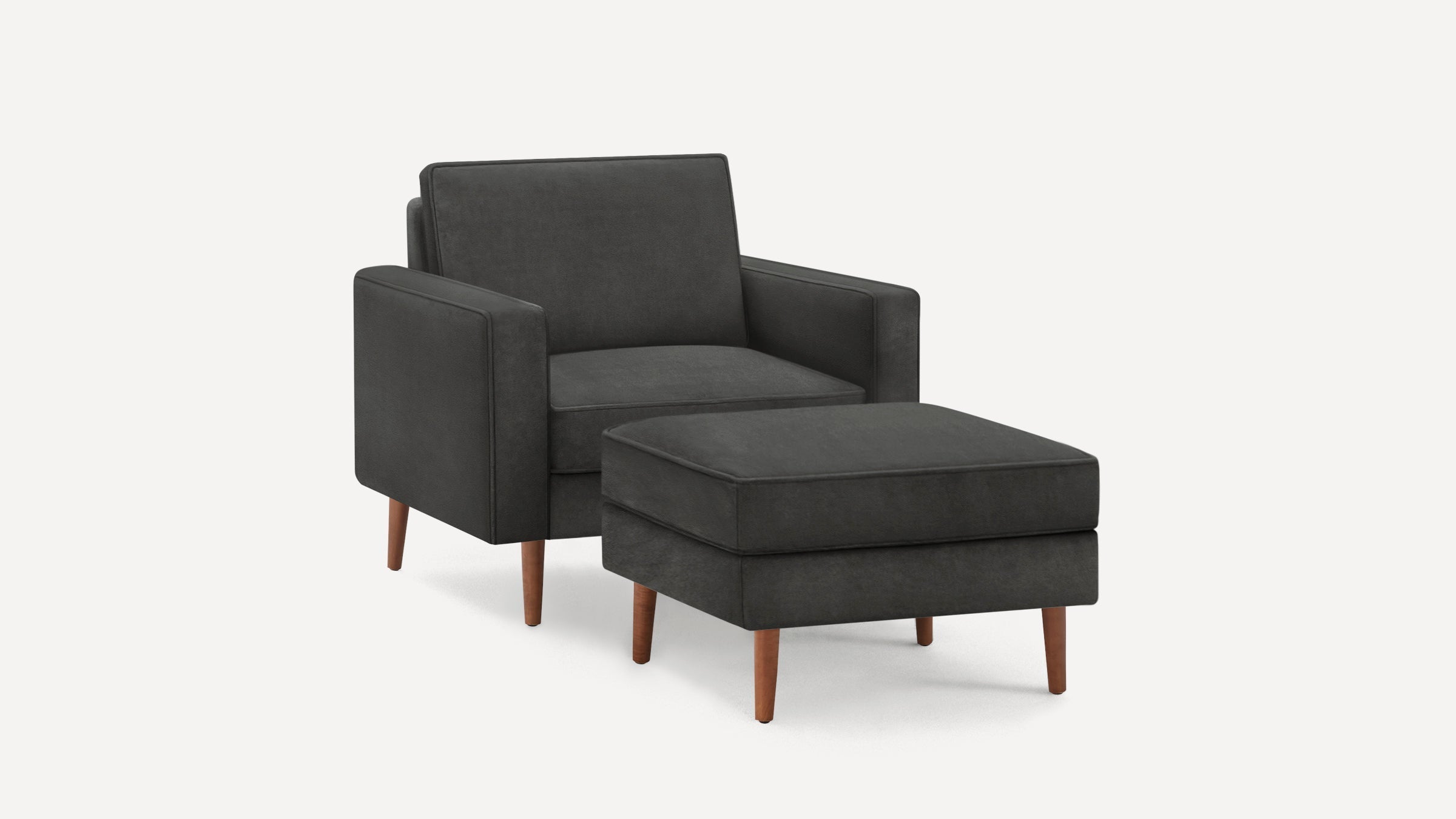 Dark gray upholstered armchair with matching ottoman, featuring wooden tapered legs and a modern, minimalist design.