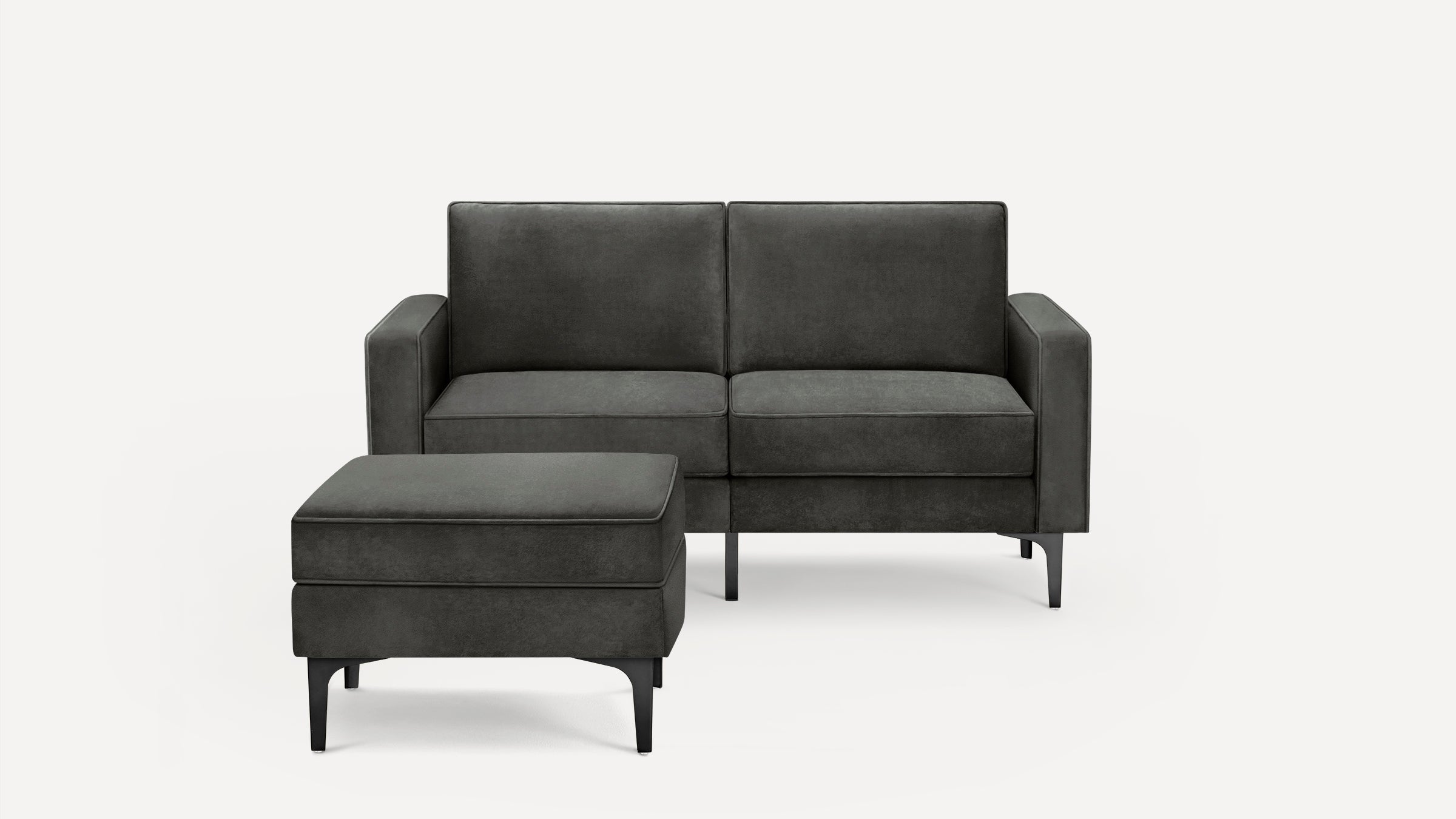 Dark gray modern sofa with matching upholstered ottoman, featuring clean lines and black metal legs on a white background.