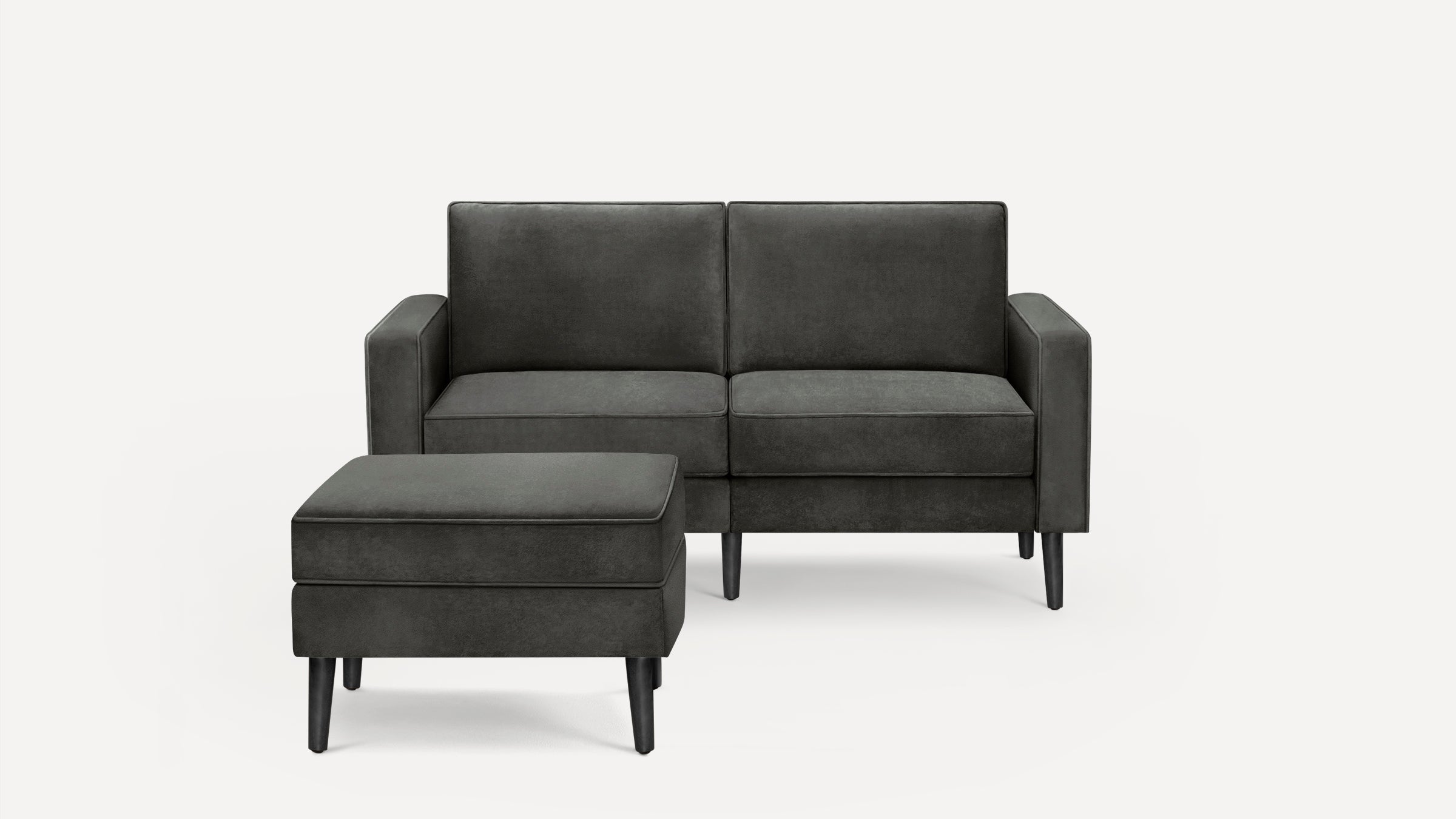Dark gray upholstered loveseat sofa with matching ottoman, featuring clean lines and black tapered wooden legs on a white background.