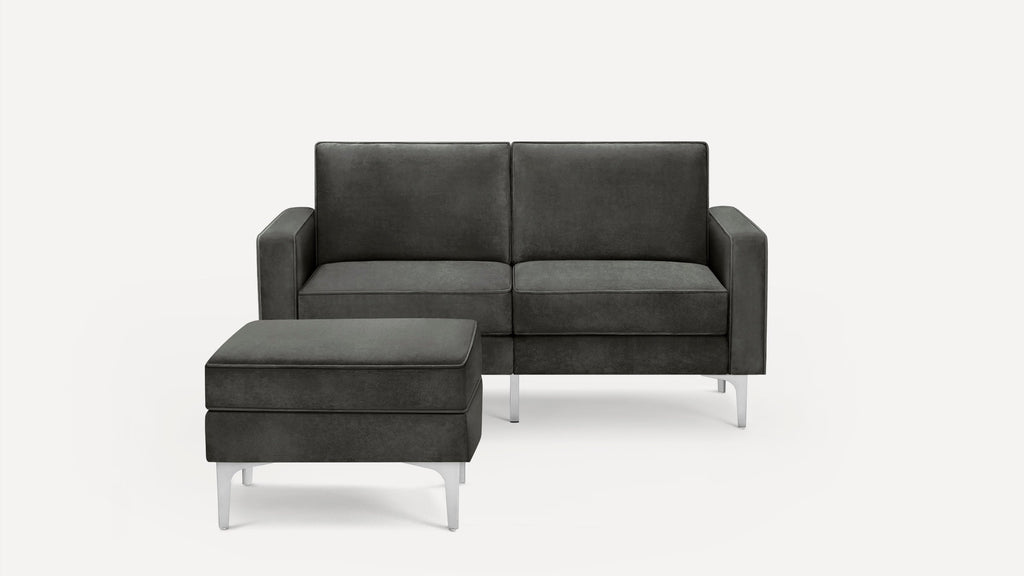 Dark gray modern loveseat with matching ottoman, featuring clean lines and metal legs on a white background.