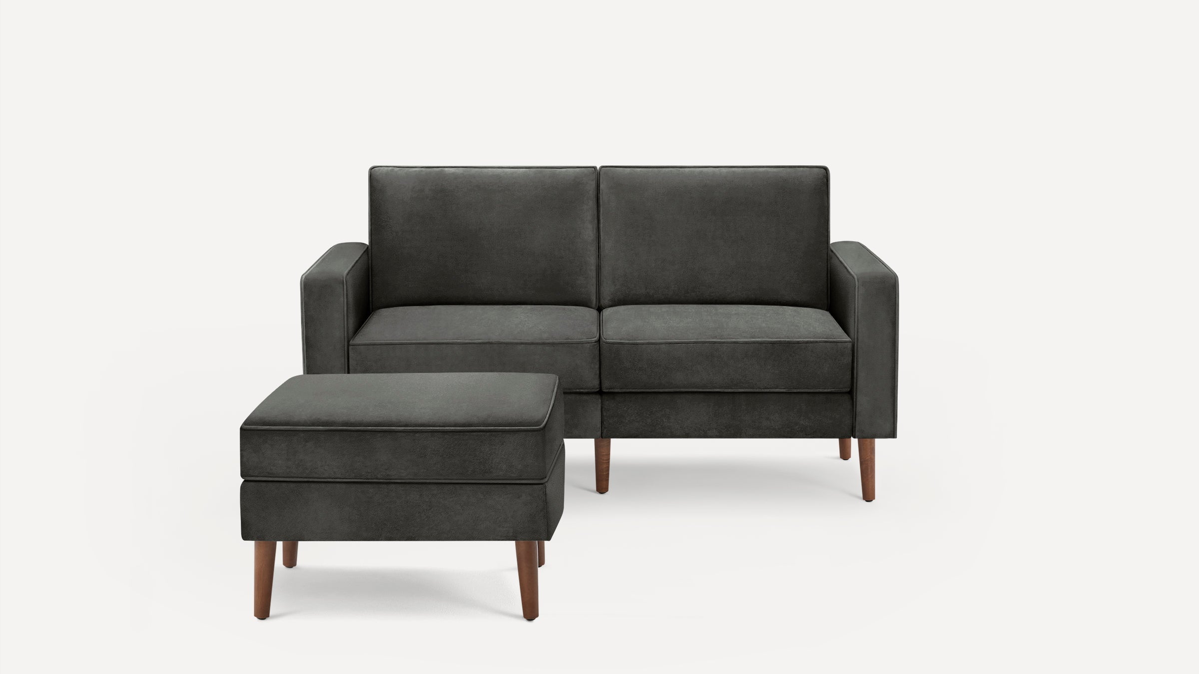 Modern dark gray two-seater sofa with matching ottoman, featuring clean lines and wooden legs on a white background.