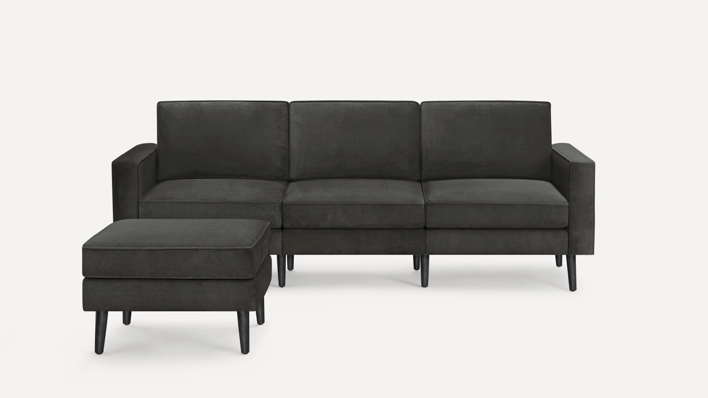 Dark gray three-seat sofa with matching ottoman, modern design, straight armrests, and black tapered legs on white background.