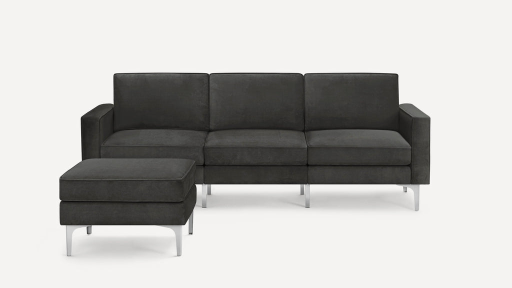 Dark gray modern three-seater sofa with matching ottoman, featuring clean lines and slim silver metal legs.
