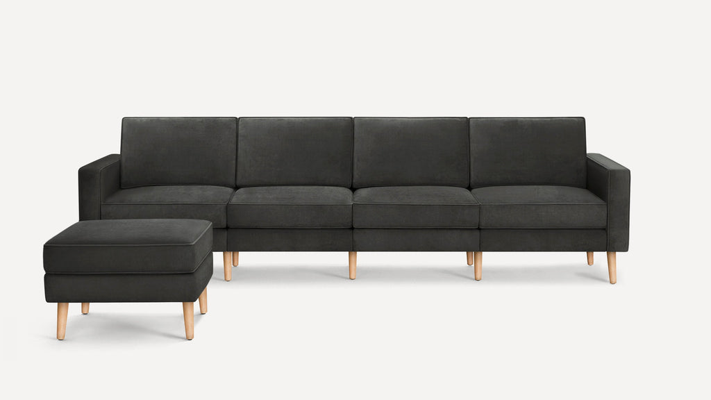 Modern dark gray fabric sectional sofa with matching ottoman, featuring clean lines and light wooden legs.