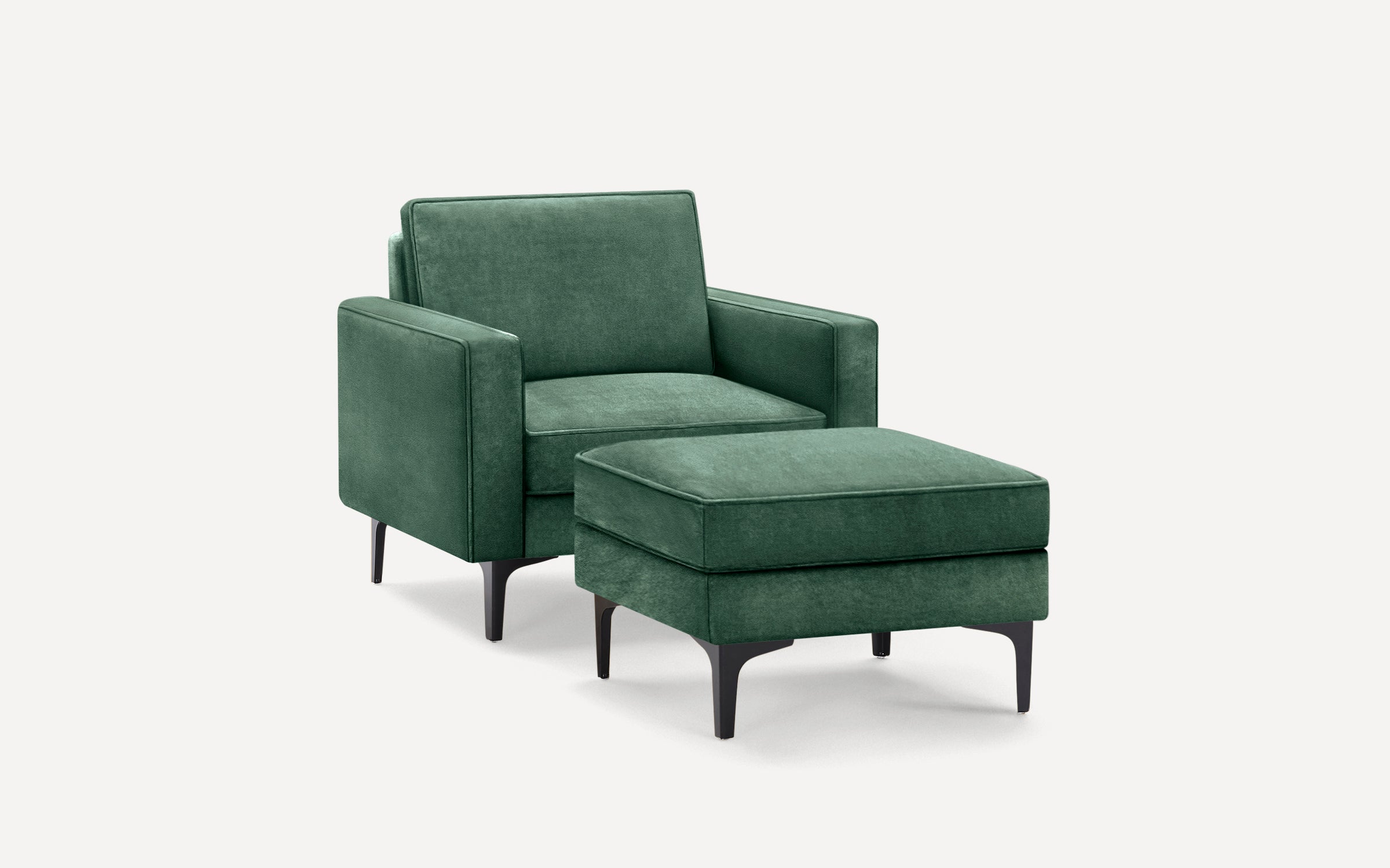 Modern green velvet armchair with matching ottoman, featuring sleek black metal legs and clean lines on a white background.