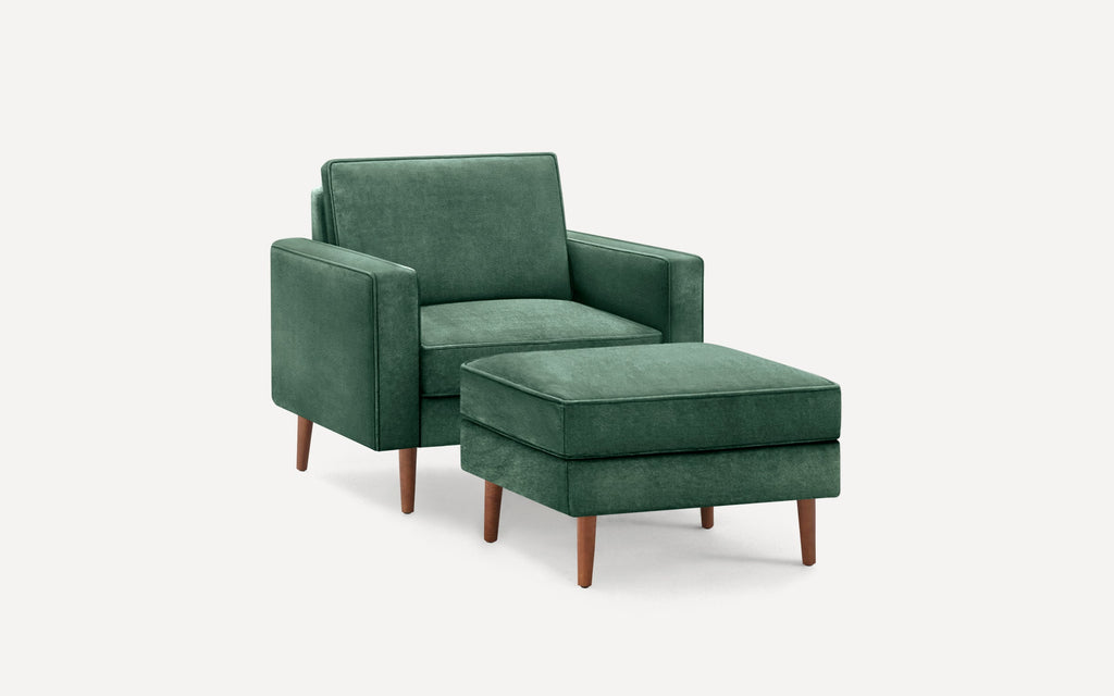 Green upholstered armchair with matching ottoman, featuring wooden tapered legs and a modern, minimalist design.