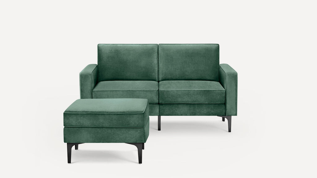 Modern two-seater green velvet sofa with matching ottoman, featuring slim black metal legs and clean lines against a white background.