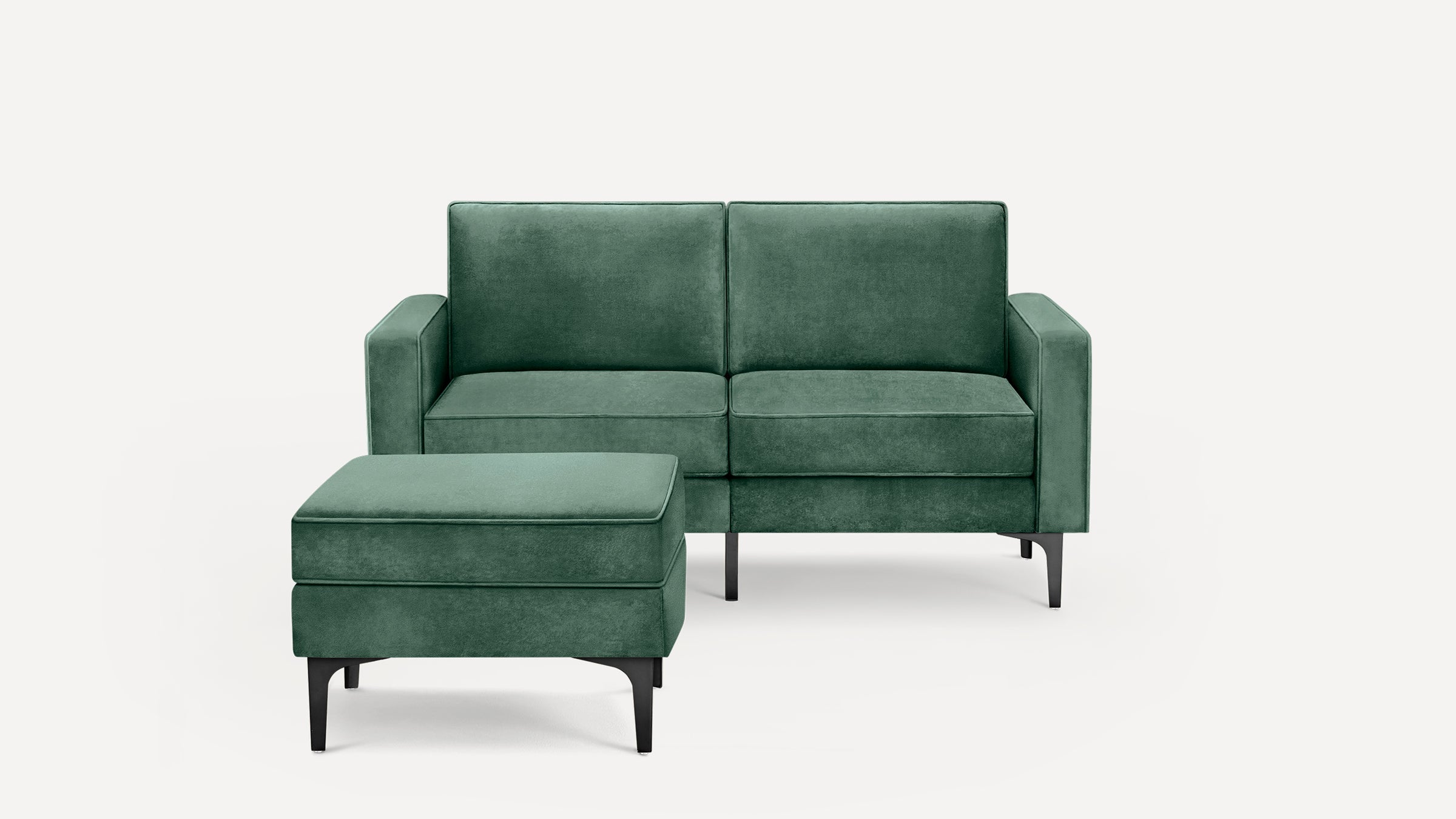 Modern two-seater green velvet sofa with matching ottoman, featuring slim black metal legs and clean lines against a white background.