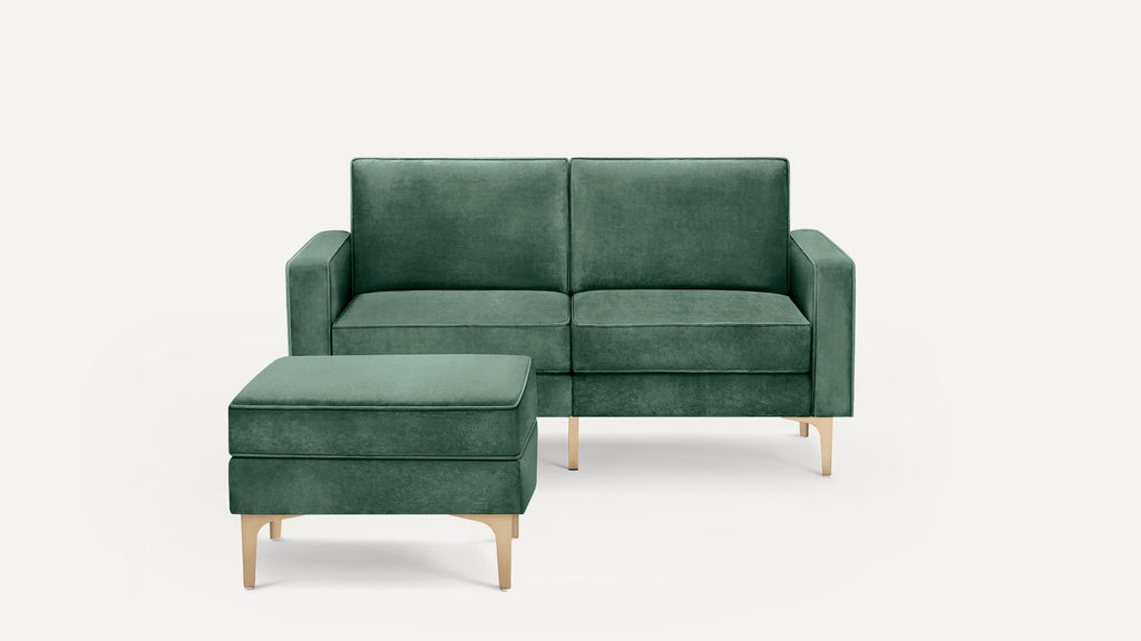 Green velvet two-seat sofa with matching ottoman, both featuring sleek gold legs on a white background.