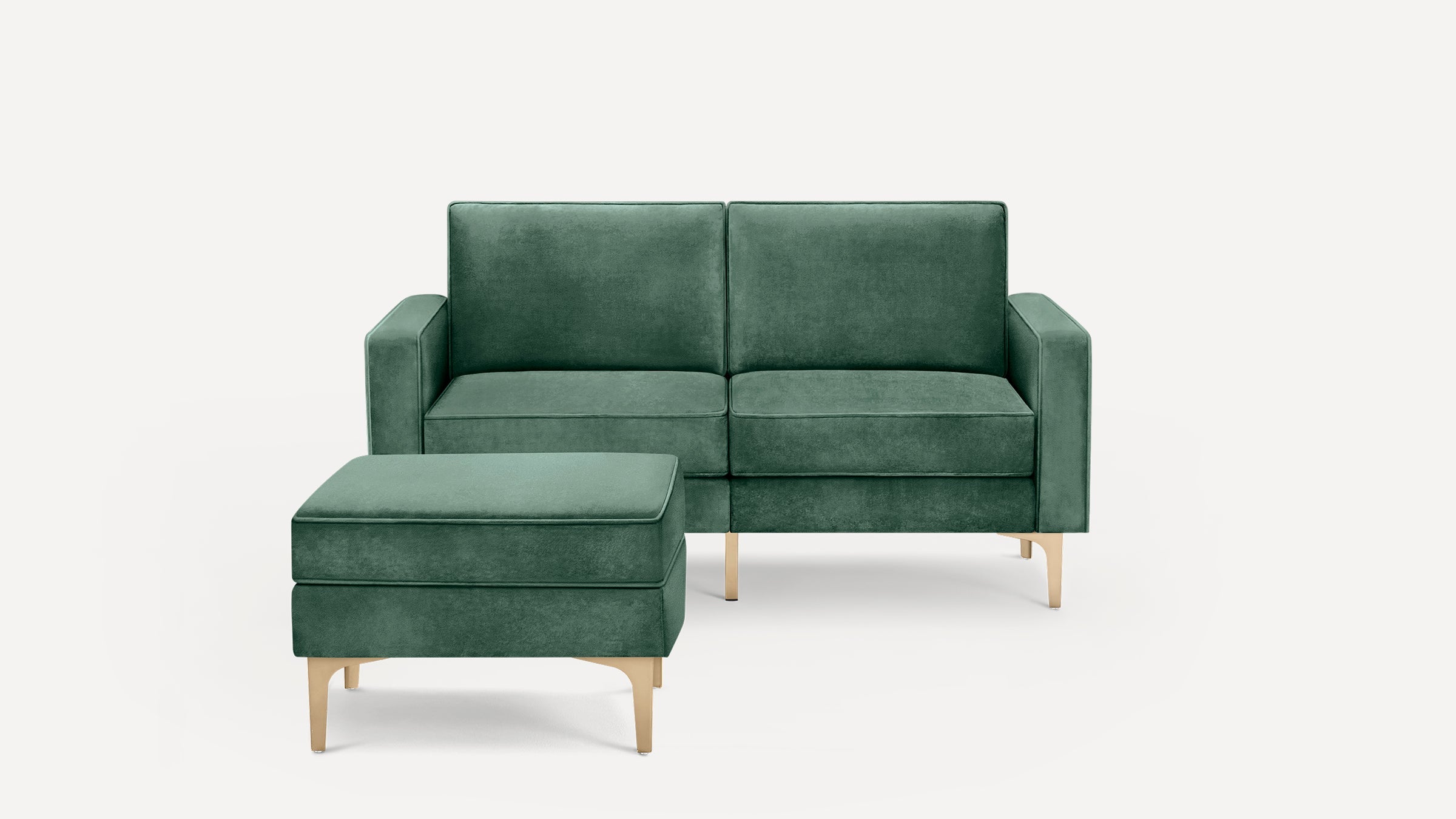 Green velvet two-seat sofa with matching ottoman, both featuring sleek gold legs on a white background.