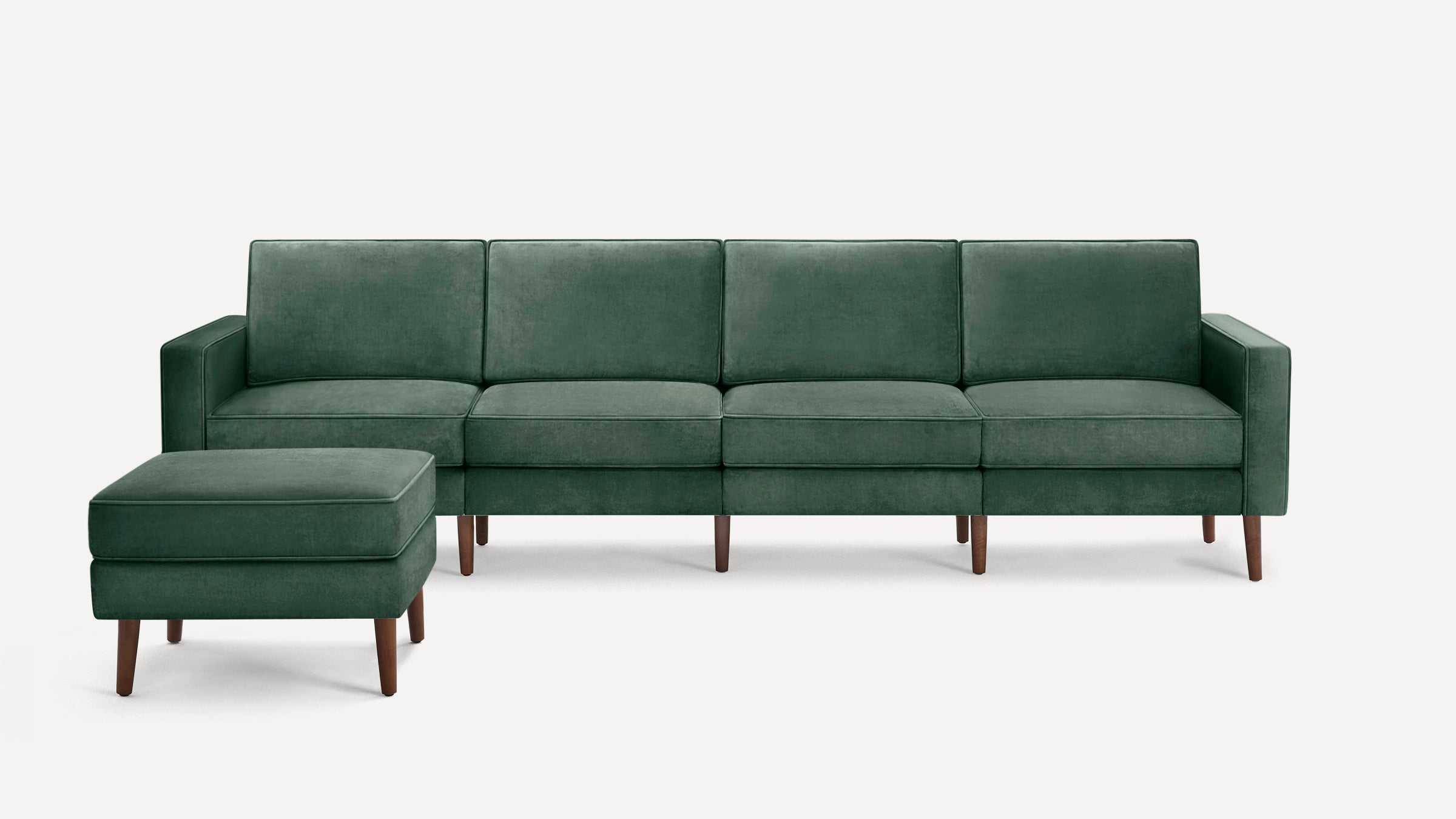 Dark green velvet sectional sofa with clean lines and wooden legs, accompanied by a matching ottoman.