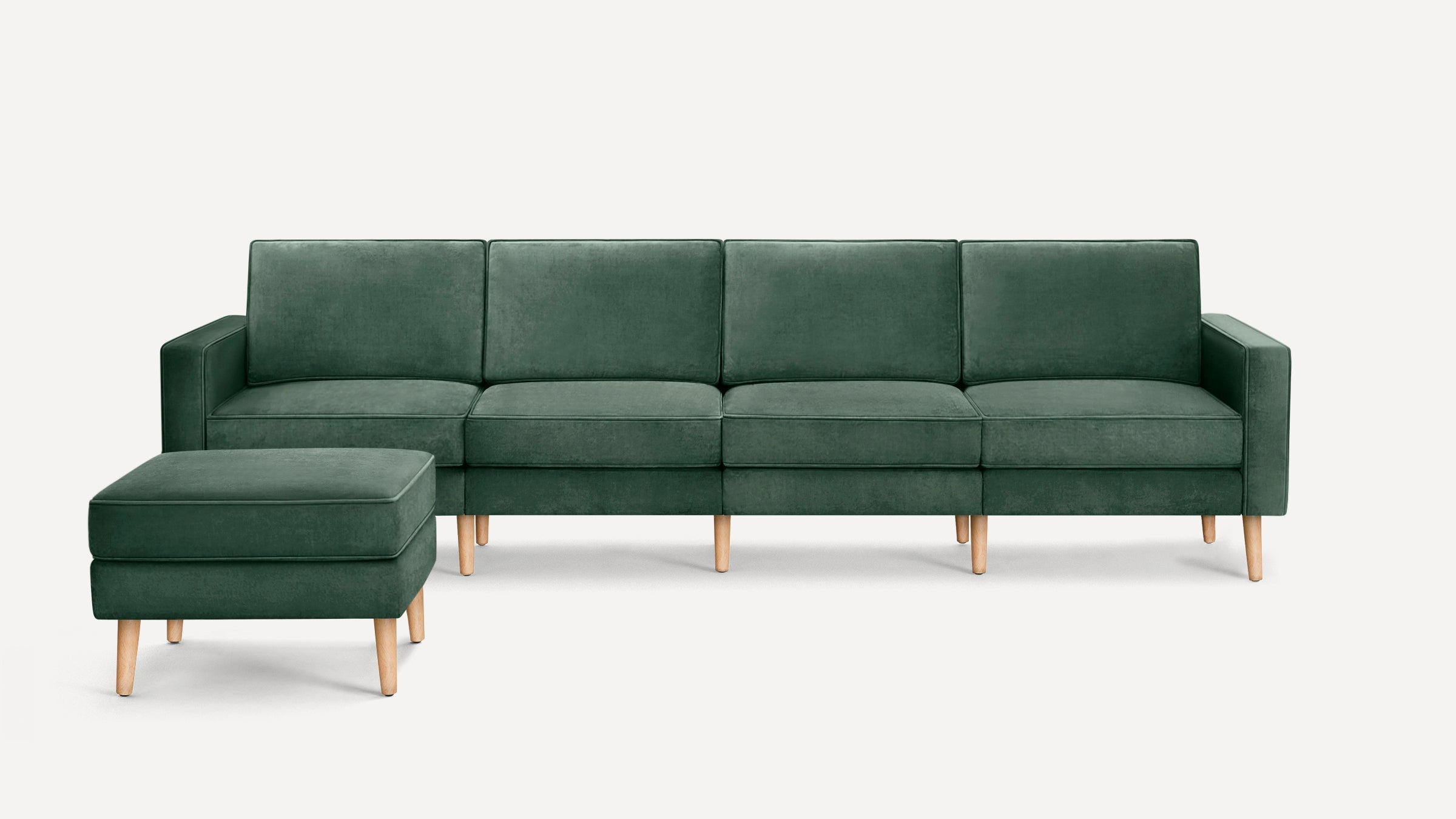 Modern dark green velvet four-seater sofa with matching ottoman, featuring wooden legs and clean, minimalist design.