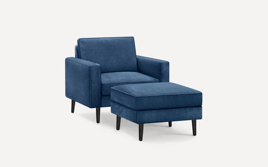 Blue upholstered armchair with matching ottoman, featuring clean lines and black tapered wooden legs.