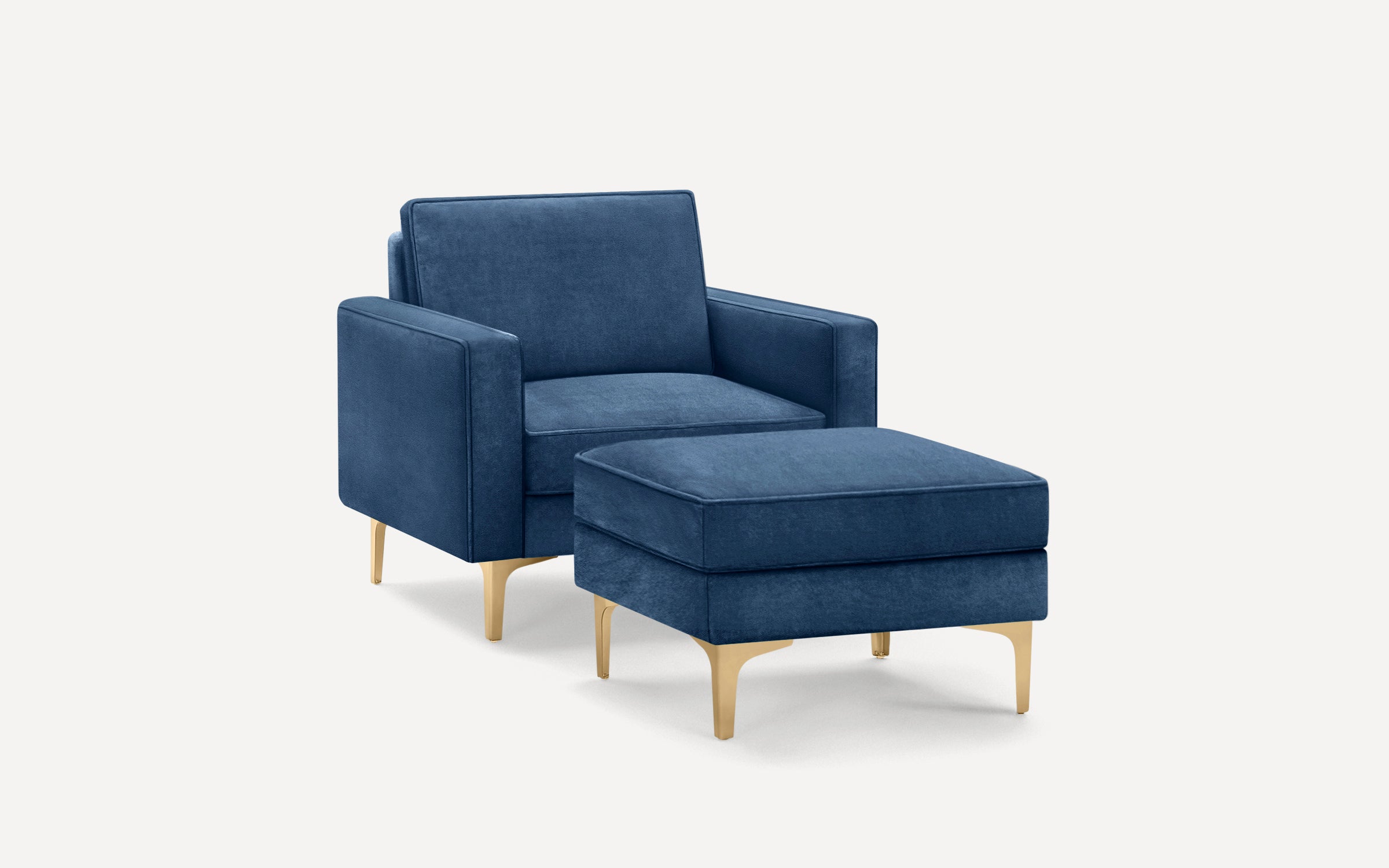 Modern navy blue upholstered armchair with matching ottoman, featuring sleek gold metal legs and clean-lined design.