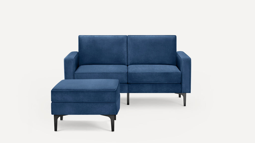 Modern blue velvet loveseat with matching ottoman, featuring clean lines and black metal legs on a white background.