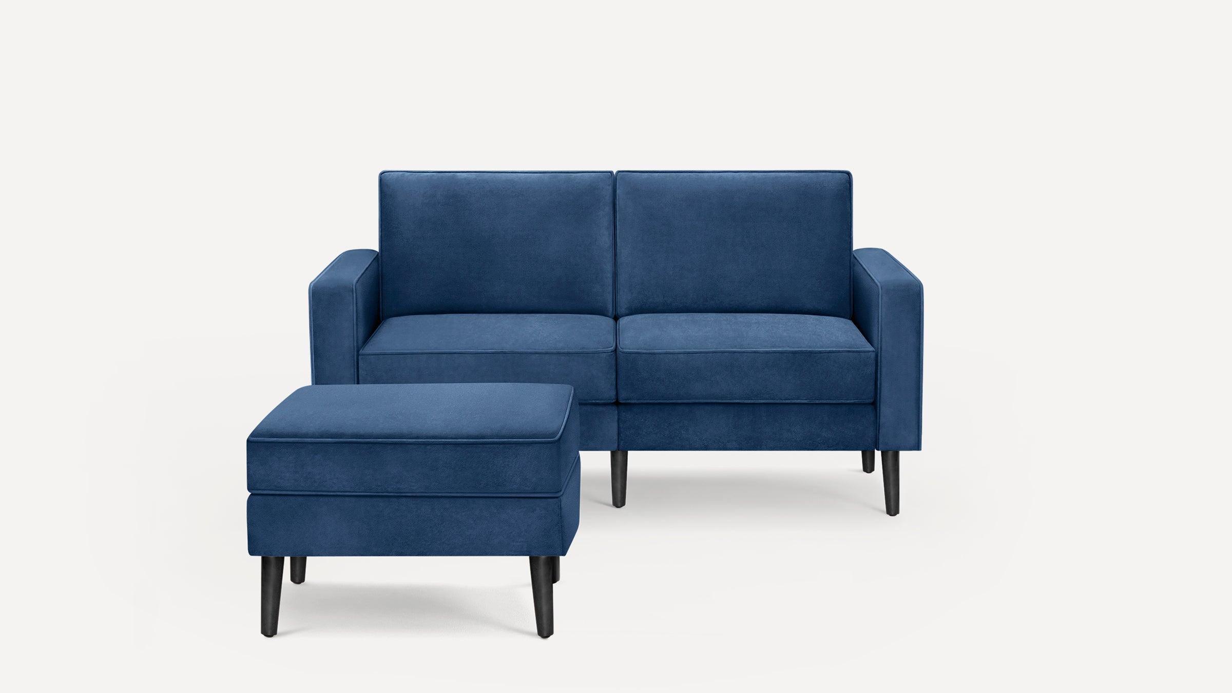 Blue velvet two-seater sofa with matching ottoman, featuring clean lines and black tapered wooden legs.