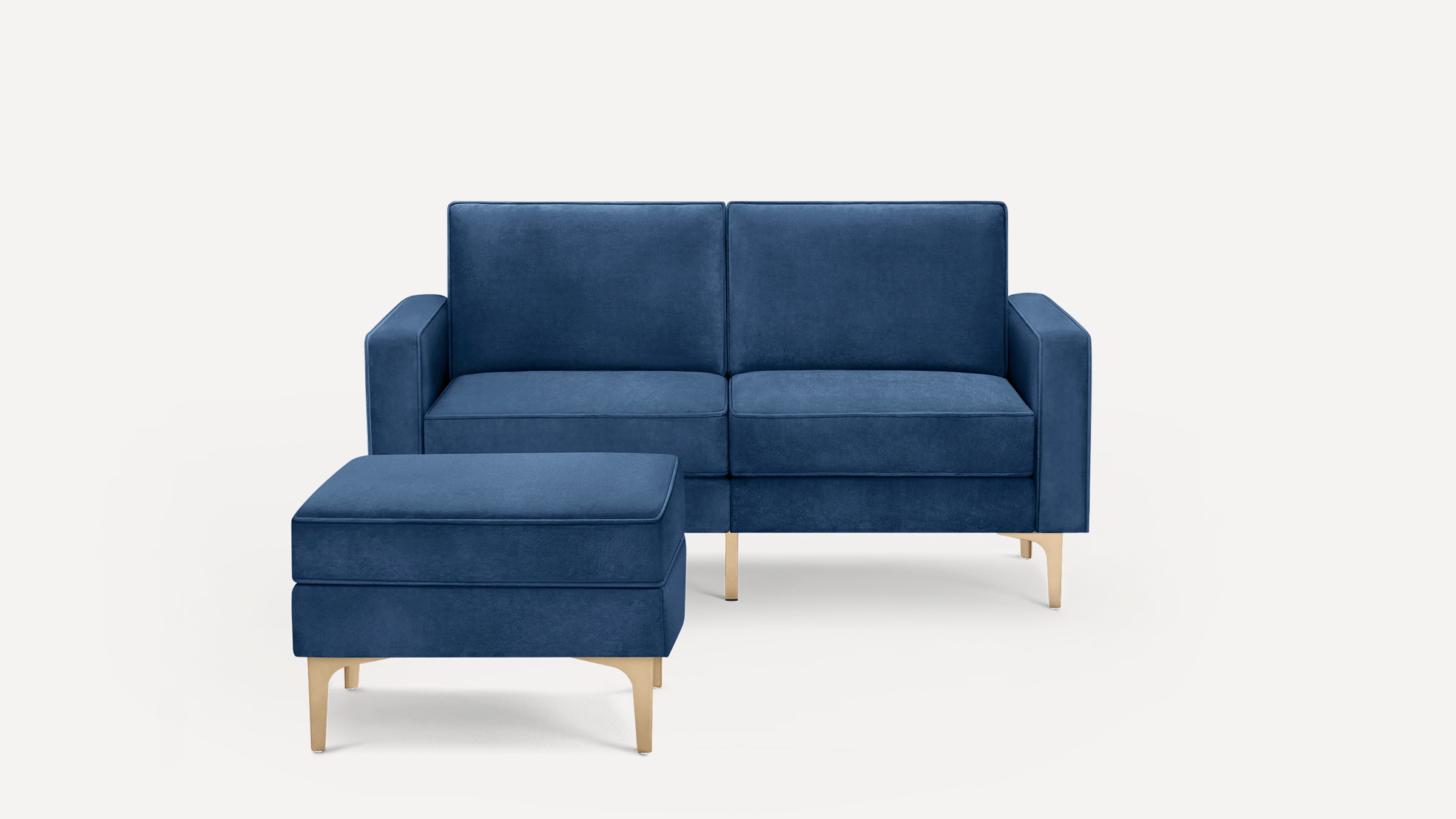 Blue velvet loveseat sofa with matching rectangular ottoman, both featuring gold metal legs, shown against a white background.