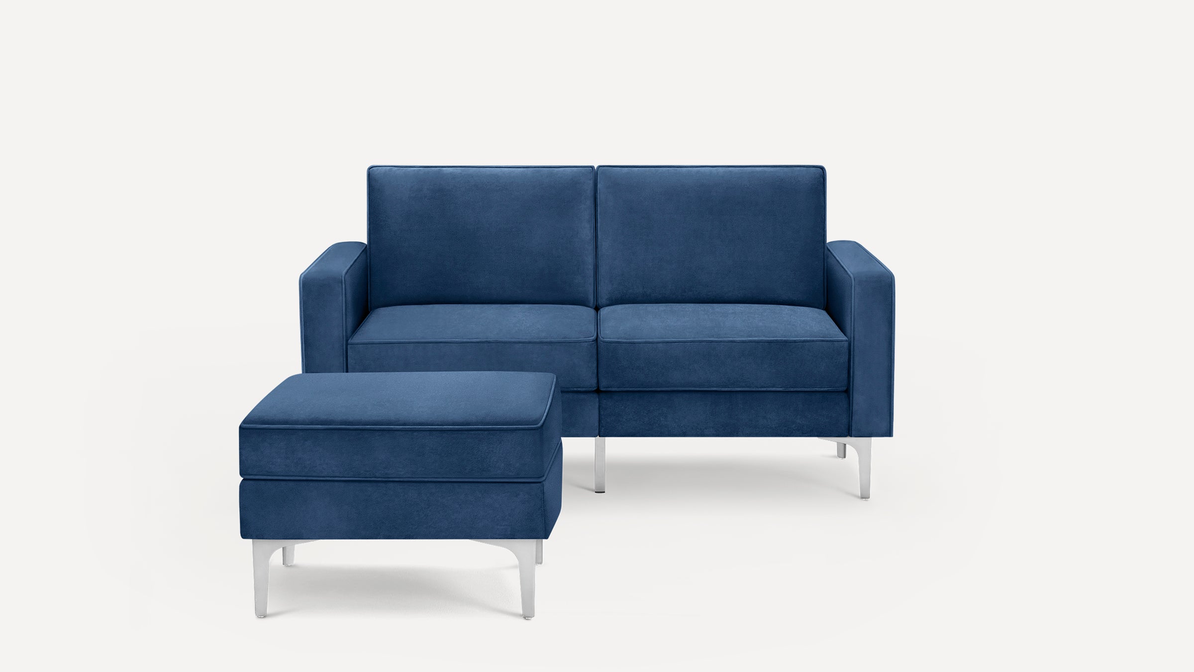 Blue velvet modern loveseat sofa with matching ottoman, featuring clean lines and silver metal legs on a white background.