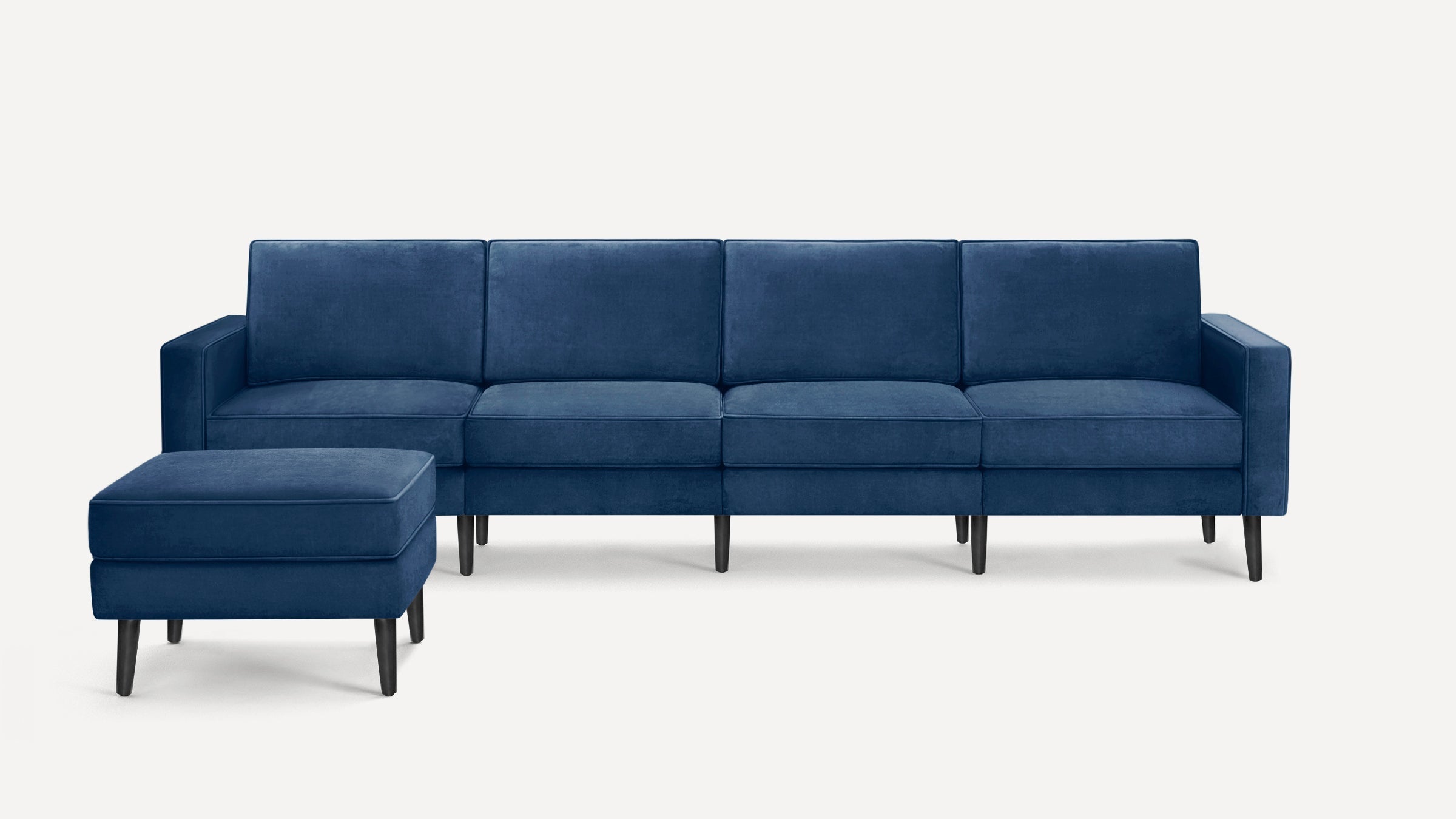 Blue velvet four-seater sofa with matching rectangular ottoman, featuring slim black legs and clean, modern design.