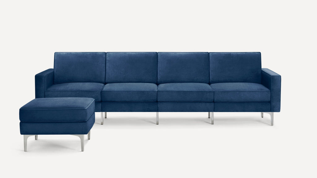 Modern navy blue velvet sectional sofa with matching ottoman, featuring clean lines and silver metal legs on white background.