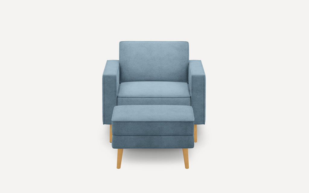 Blue upholstered armchair with matching ottoman, featuring clean lines and light wooden tapered legs.