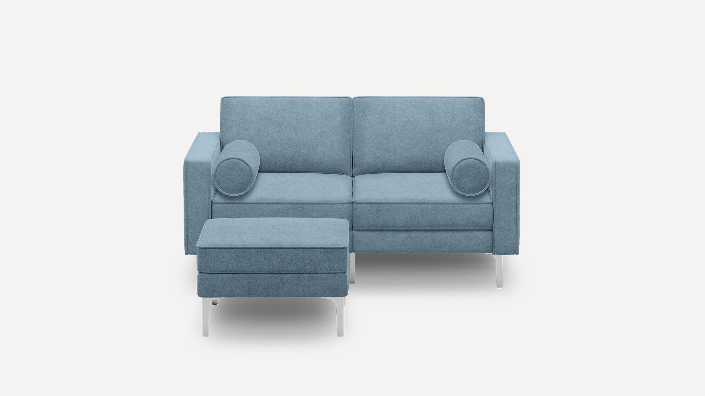 Modern light blue upholstered two-seater sofa with matching ottoman, slim silver legs, and round bolster pillows on each side.
