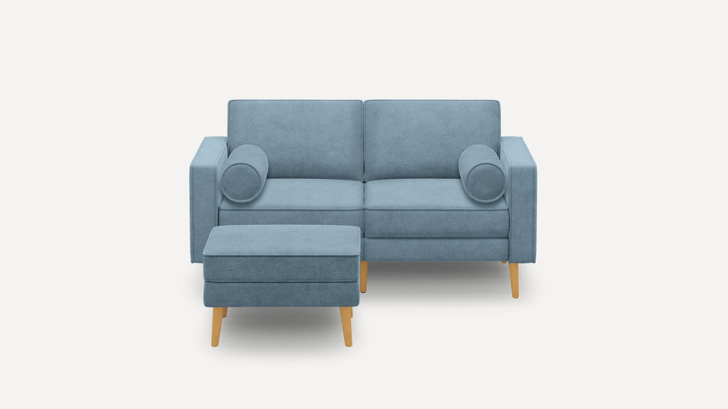 Light blue fabric loveseat with two round bolster pillows and matching rectangular ottoman, all featuring wooden legs.