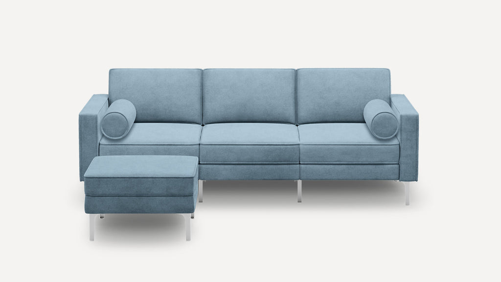 Modern light blue fabric sectional sofa with clean lines, square arms, metal legs, and two round bolster pillows.