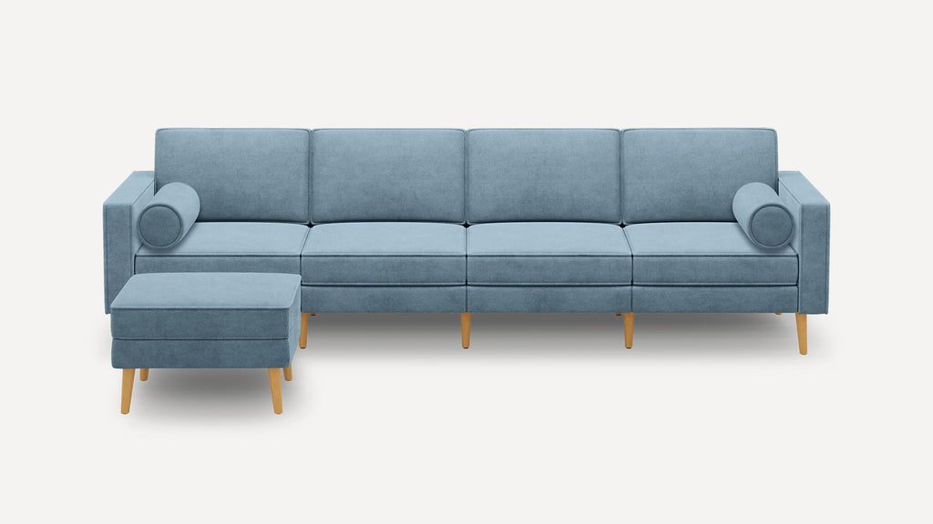 Modern light blue sectional sofa with wooden legs, includes matching ottoman and two cylindrical bolster pillows.
