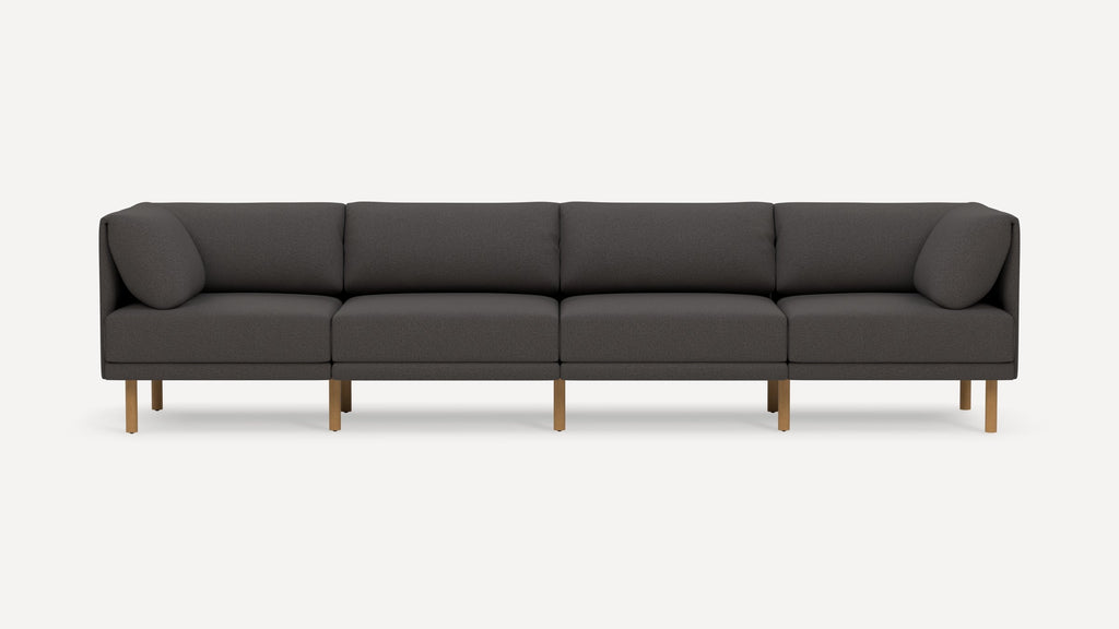 Four-seater modern dark gray fabric sofa with wooden legs and rounded armrest cushions on each end.