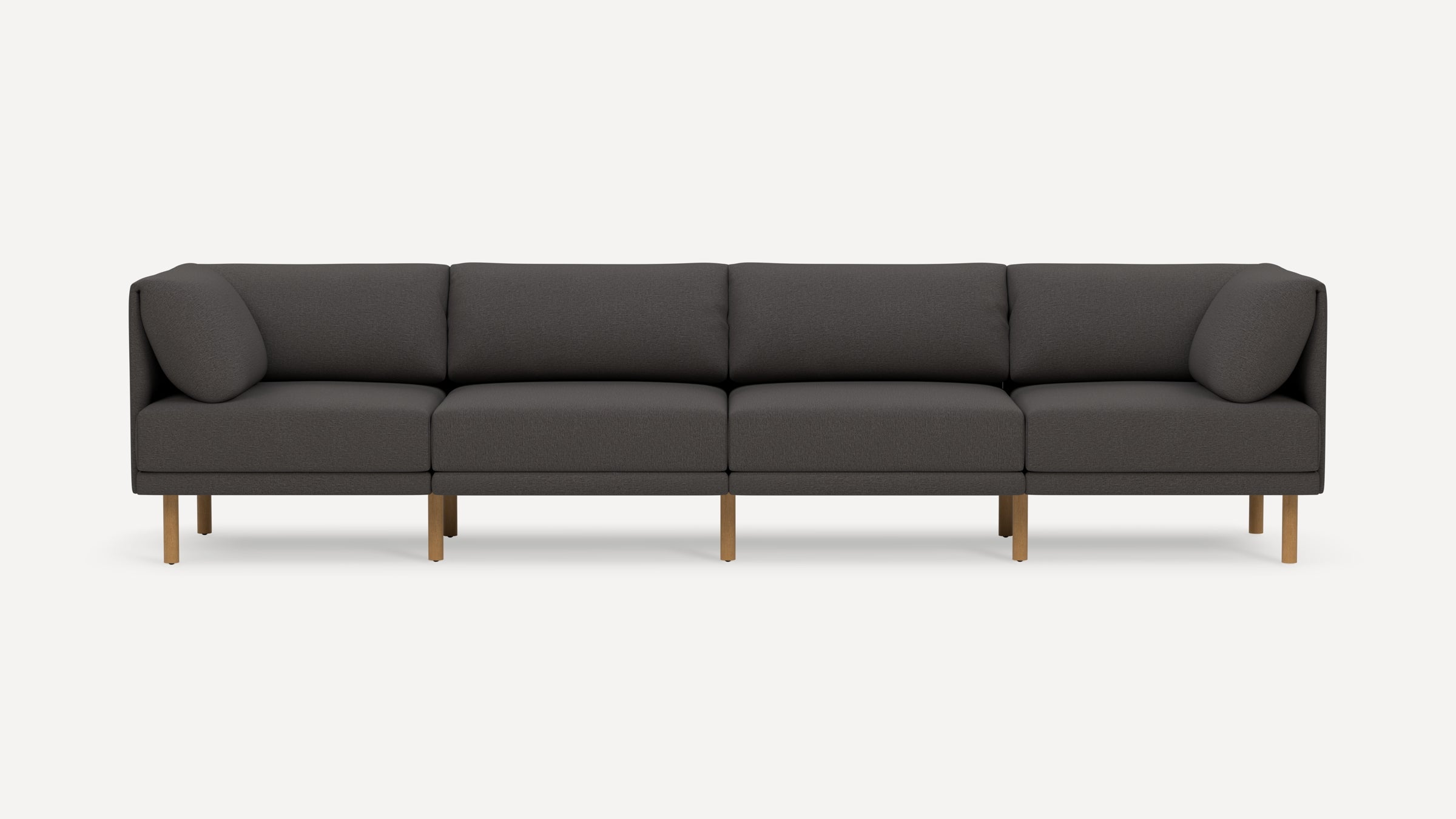 Four-seater modern dark gray fabric sofa with wooden legs and rounded armrest cushions on each end.