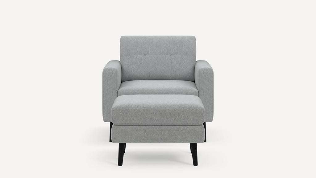 Modern light gray fabric armchair with straight arms, tufted backrest, cushioned seat, and black tapered legs, front view.