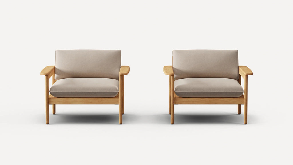 Two identical armchairs with light wooden frames and beige cushioned seats and backrests, against a plain white background.
