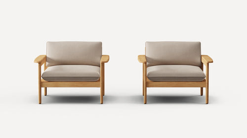 Two identical armchairs with light wooden frames and beige cushioned seats and backrests, against a plain white background.