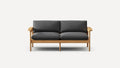 Two-seater sofa with dark gray cushions and a natural wooden frame, featuring simple, modern design and armrests.