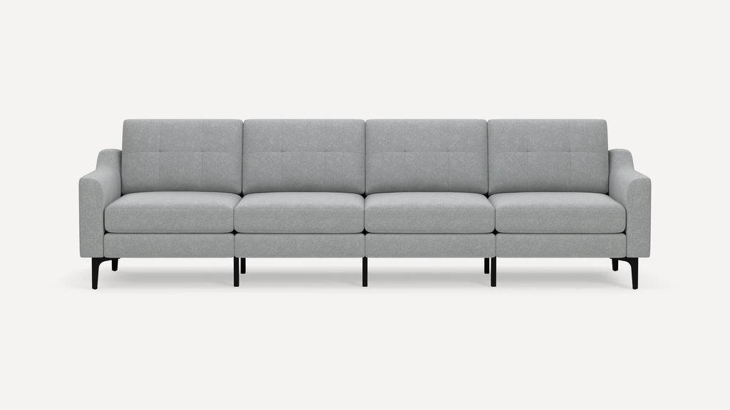 Modern light gray fabric four-seater sofa with tufted back cushions, clean lines, tapered black legs, and slightly angled armrests.