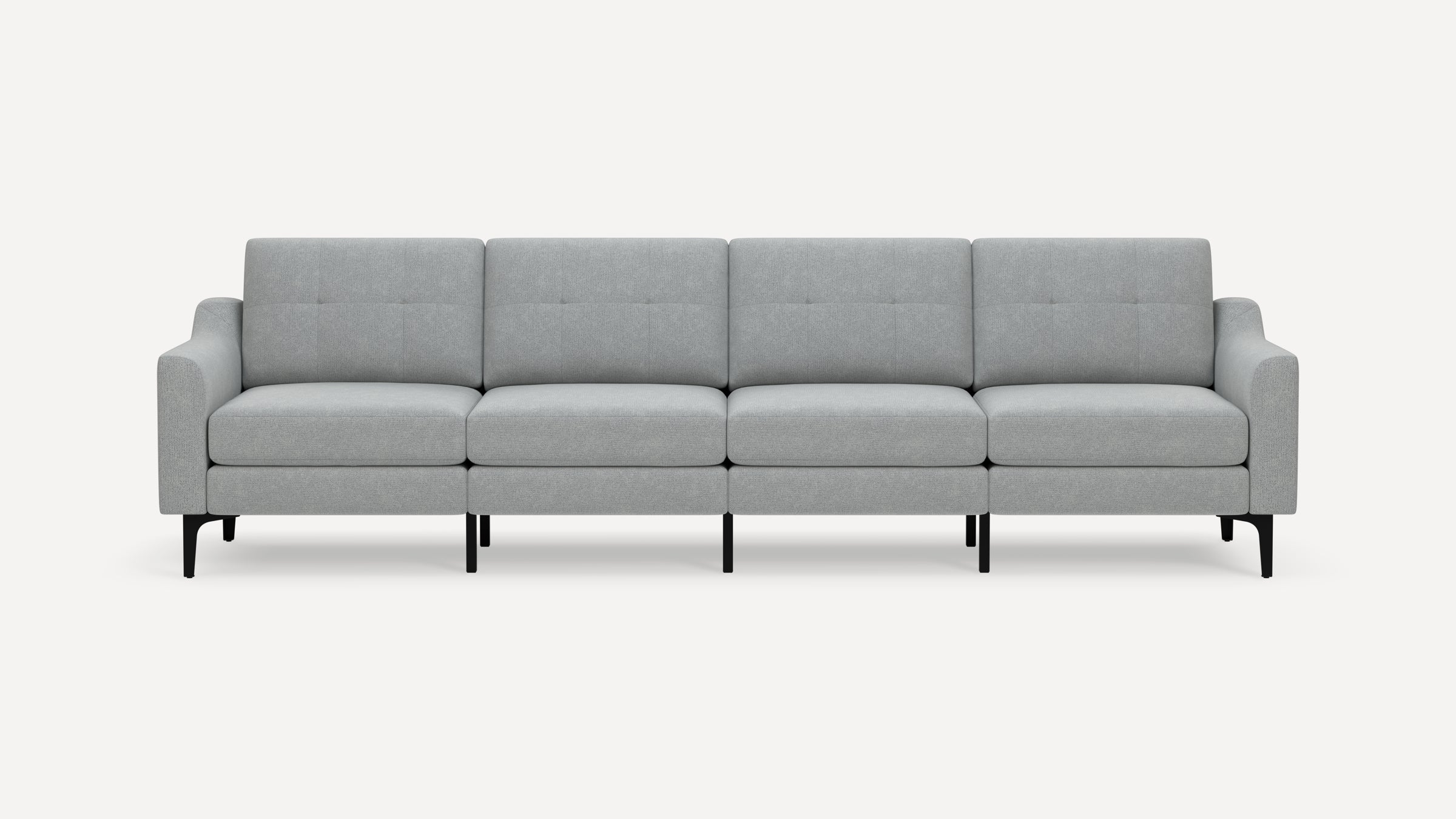 Modern light gray fabric four-seater sofa with tufted back cushions, clean lines, tapered black legs, and slightly angled armrests.