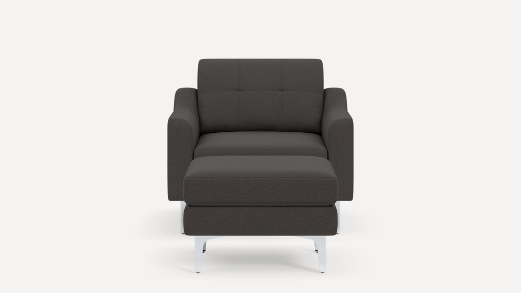 Front view of a modern dark gray upholstered armchair with matching ottoman and sleek white legs.