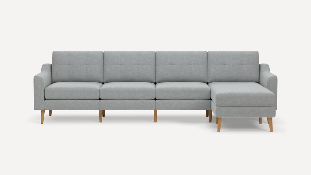 Light gray sectional sofa with wooden legs, featuring three seats and a chaise lounge on the right side.