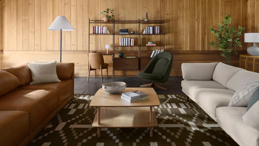 a living room with a brown leather couch, a brown coffee table, and a green armchair